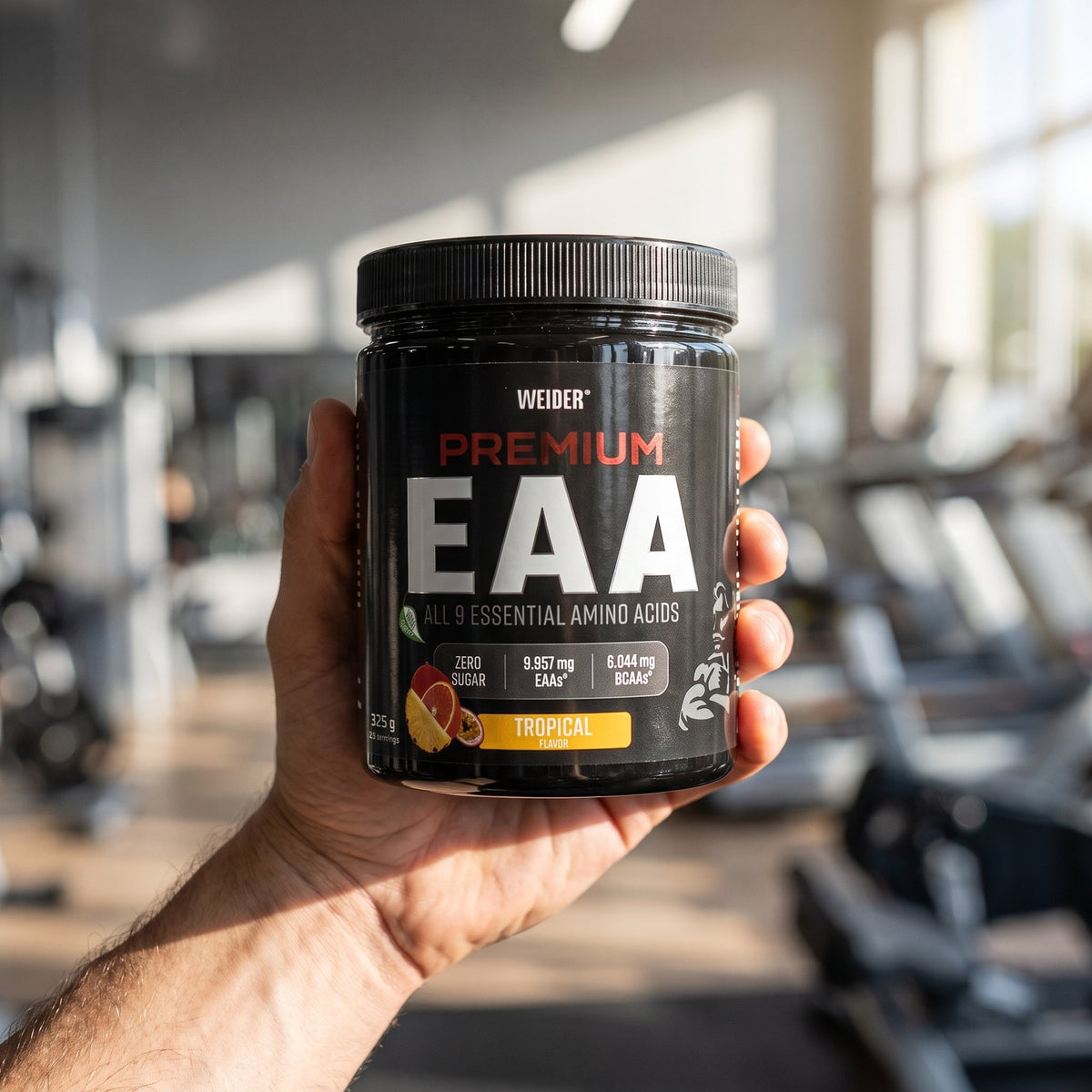 Weider Essential Amino Acids, held in the hand in a gym