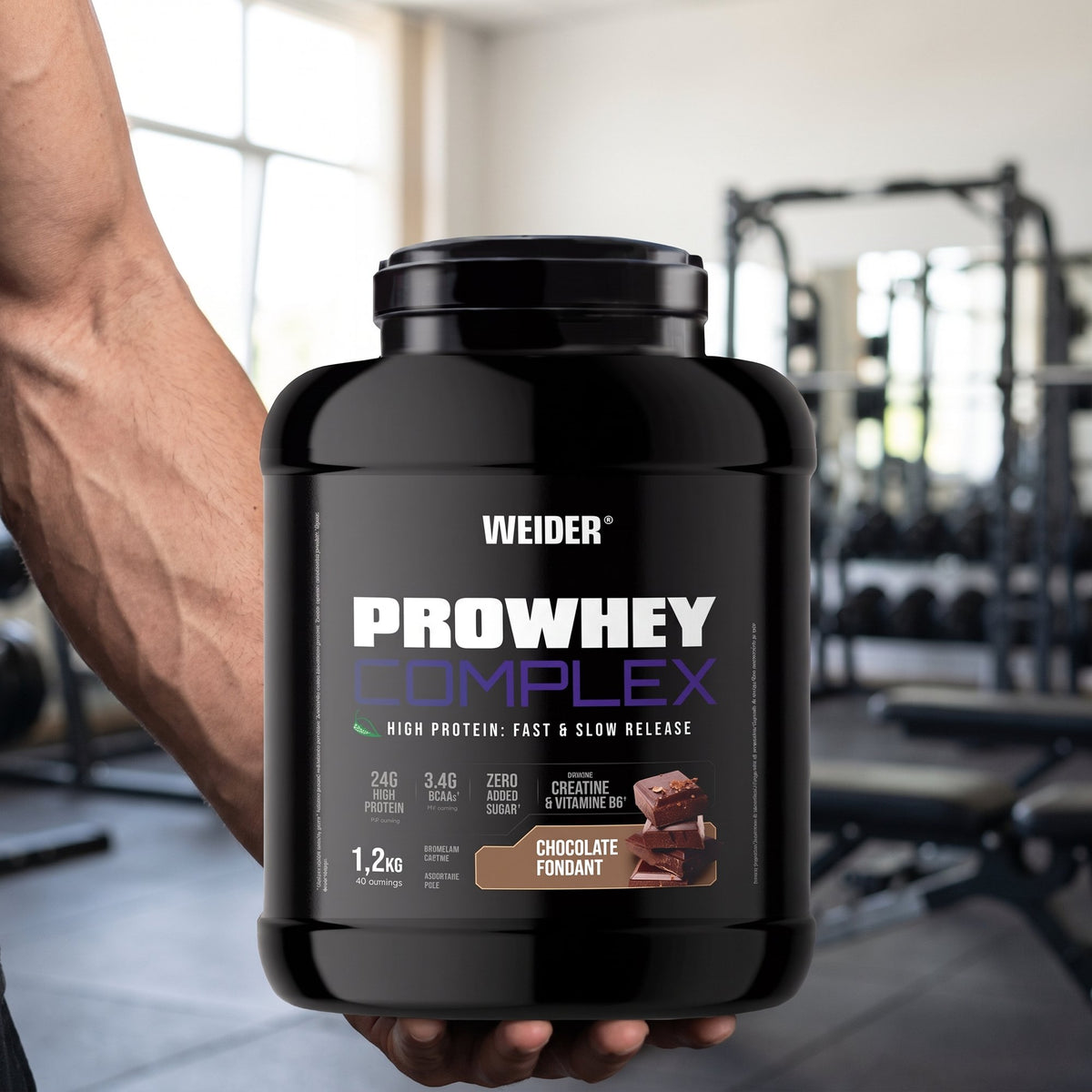 Weider Whey Protein, Everyday, held in the hand in a gym