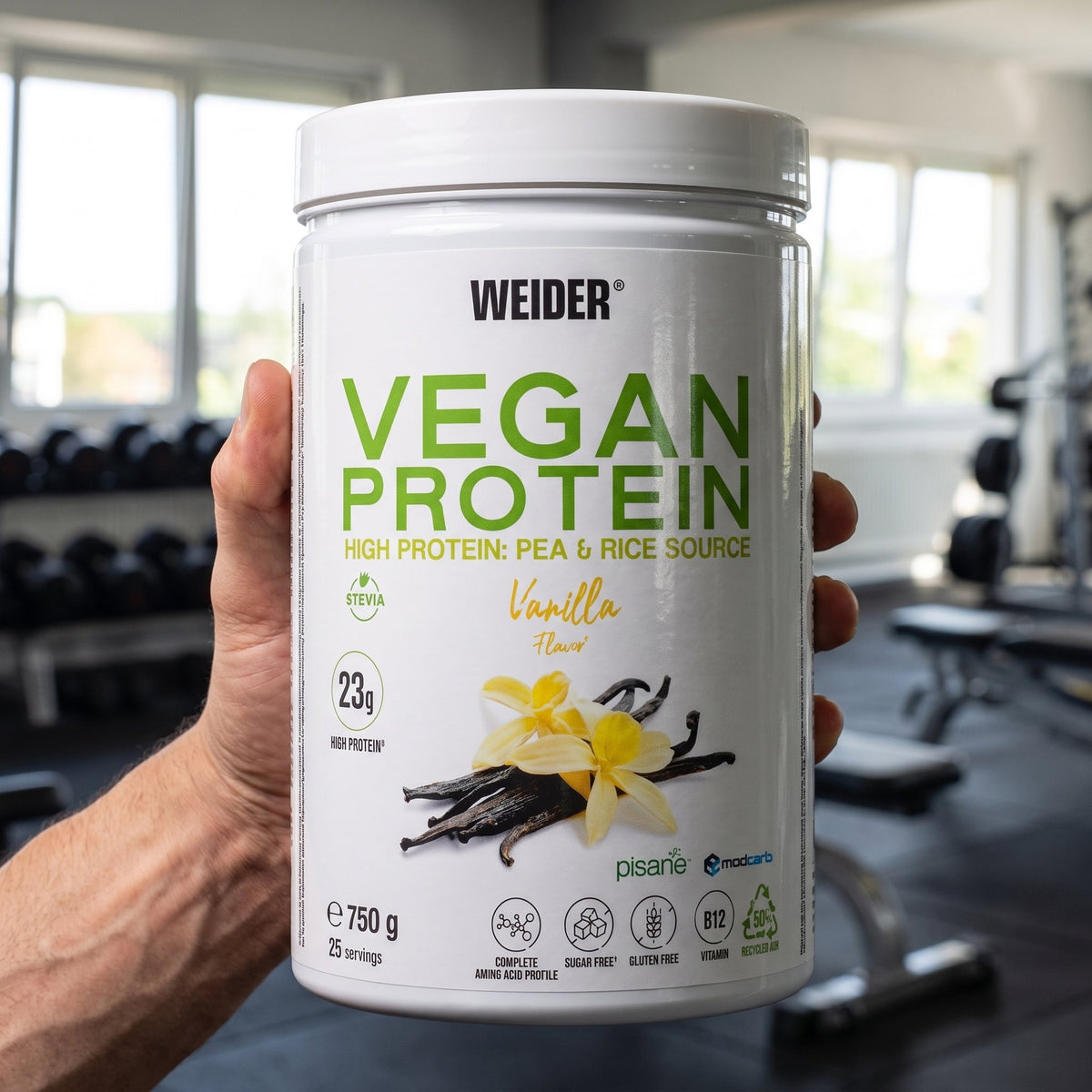Weider Plant Protein, held in the hand in a gym