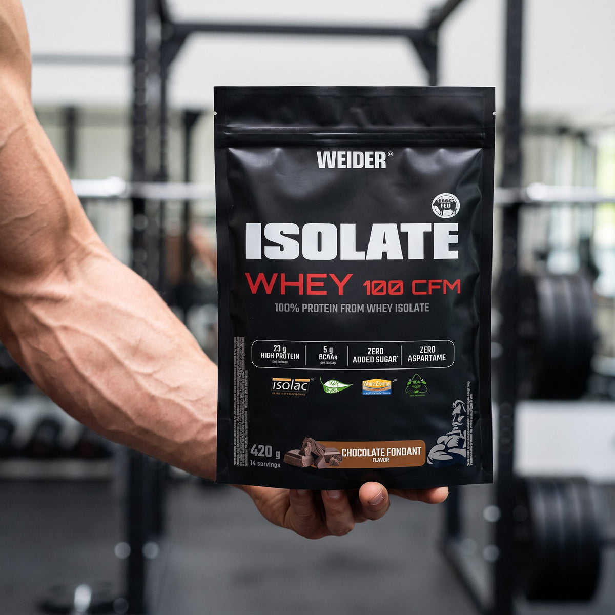 Weider Whey Protein, Isolate, held in the hand in a gym