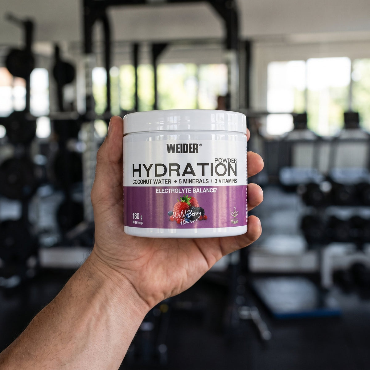 Weider Hydration Powder, held in the hand in a gym