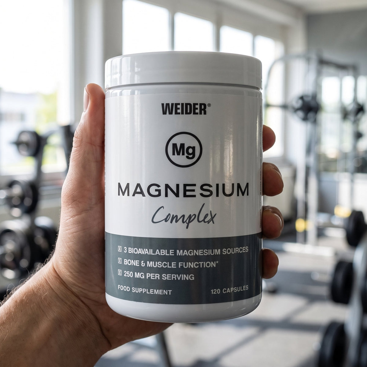 Weider Magnesium Capsules, held in the hand in a gym